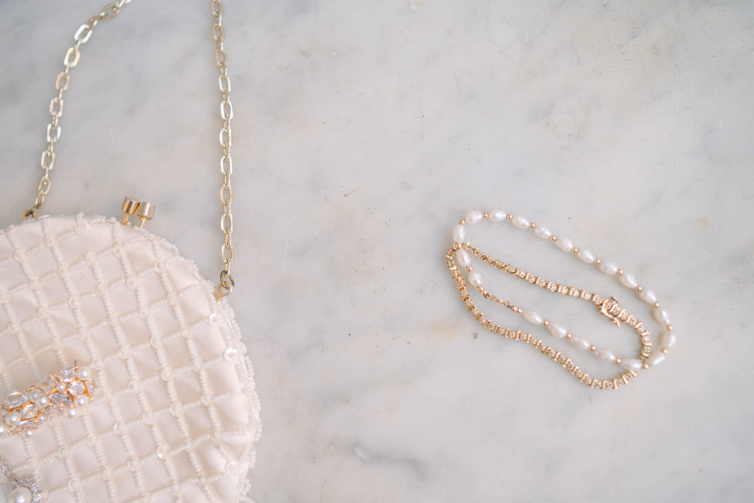 pink purse and pearls over white marbled background cover for virginia wedding photographer price