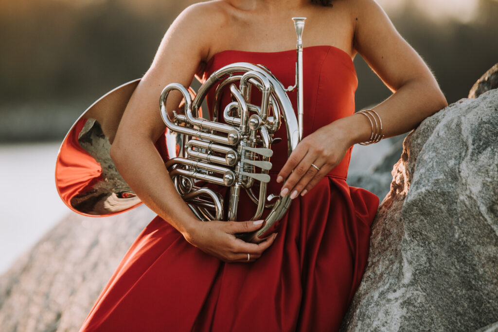 Detail close up of woman in red dress holding a French horn